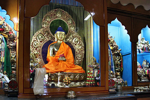 Pokhara-Shree-Gaden-Dhargay Ling Monastery13 Buddha sits behind glass on altar at Shree Gaden Dhargay Ling Monastery
