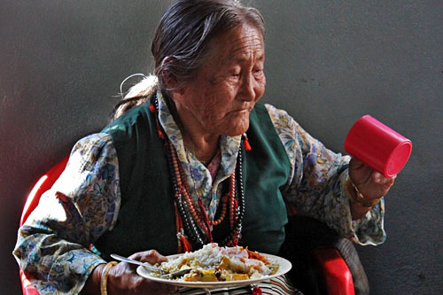 Pokhara-Tashiling-Tibetan-Refugee-Settlement-Human-Rights-Day2 Tibetan woman enjoys meal at International Human Rights Day Celebration at Tashiling Tibetan refugee settlement in Pokhara, Nepal