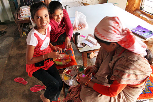Pokhara-Tihar-Tika-Ceremony10 Himrekha (left) and Annapurna (center) help their aunt Laxmi prepare the powdered pigments used to make tikas